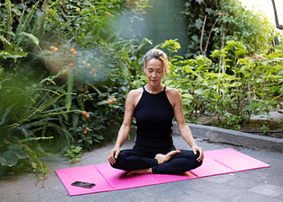 Woman does a Peloton Yoga class on exercise mat 