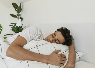 A man sleeping in bed in a bright, sunny room.