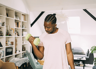 A man doing single-arm bicep curls with a dumbbell at home.