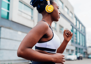 A woman jogging with headphones on outside. Jogging can be a form of mindful movement.