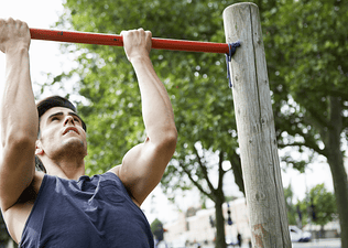 Man doing a reverse pull up exercise outdoors