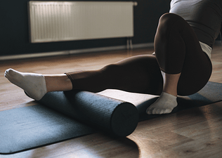 A woman foam rolling her right calf before a workout.