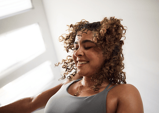 A close-up photo of a happy woman feeling confident during a workout. 