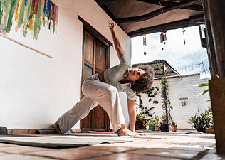 A woman doing a Runner's Lunge Twist while practicing yoga on an outdoor patio as part of her Sunday reset routine.