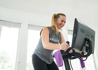Smiling woman rides Peloton Bike