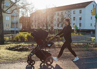 A new mom going for a walk outdoors with her baby in a stroller.