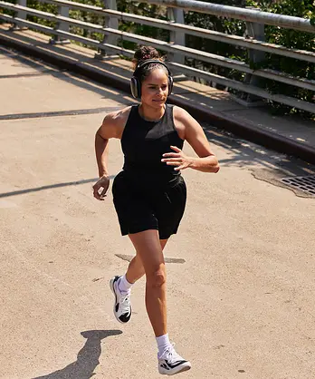 A woman running on an outdoor bridge on a sunny day.
