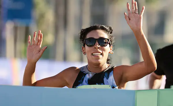 Woman crossing the finish line of a race after setting a running goal.