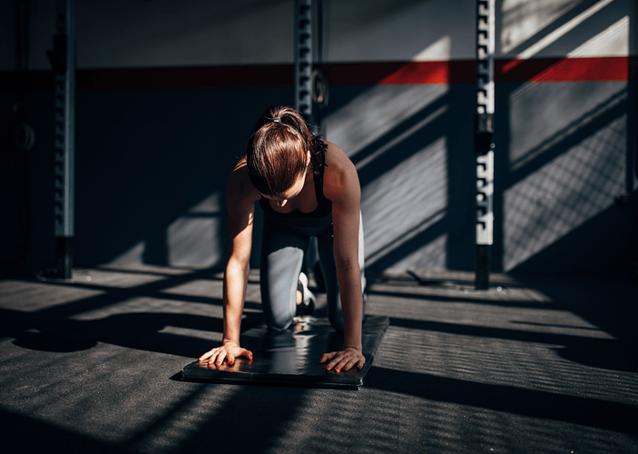 Woman preparing to do a bear plank core exercise during a workout at the gym.