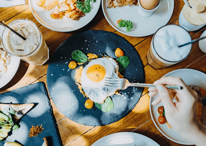 Birds-eye view of someone eating a sunny-side-up egg (a complete protein) at an outdoor restaurant.