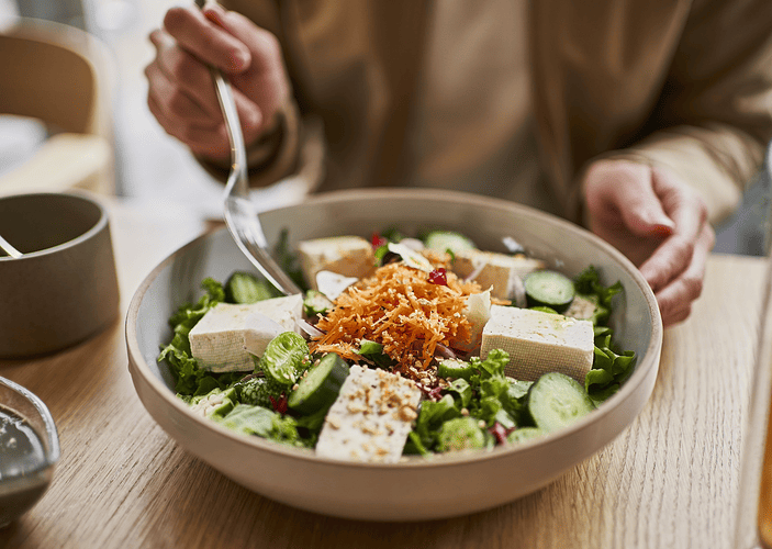 A woman enjoying a lean protein tofu bowl.