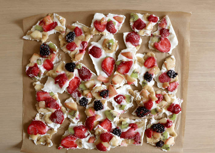 A tray of vegan Greek yogurt bark with various fruits in it like strawberry, banana, kiwi, blackberries, and raspberries. It's a high-protein vegan snack.
