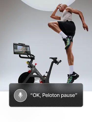 Woman in a light gray tank top and black shorts performs a high knee jump on a mat. Overlay button reads “Pause class.”