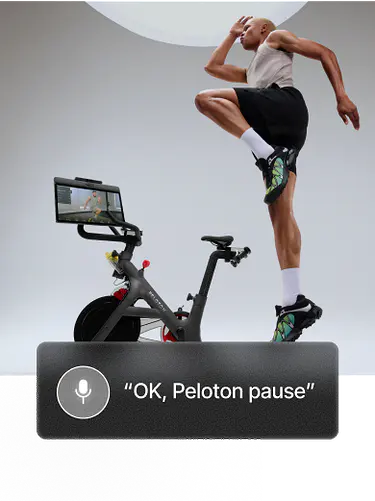 Woman in a light gray tank top and black shorts performs a high knee jump on a mat. Overlay button reads “Pause class.”