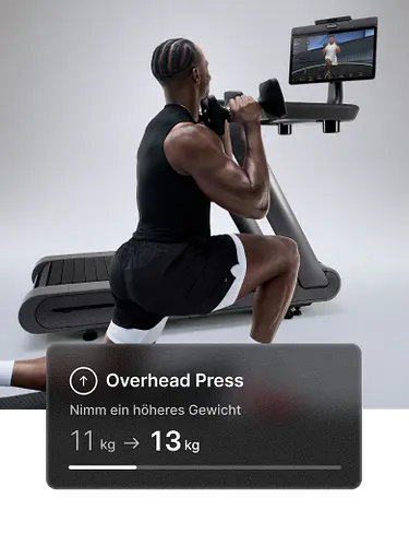 Ein Mann macht einen Ausfallschritt mit Hanteln vor einem Peloton Row+. Das Overlay empfiehlt: „Versuche ein schwereres Gewicht — 7 kg → 9kg.“