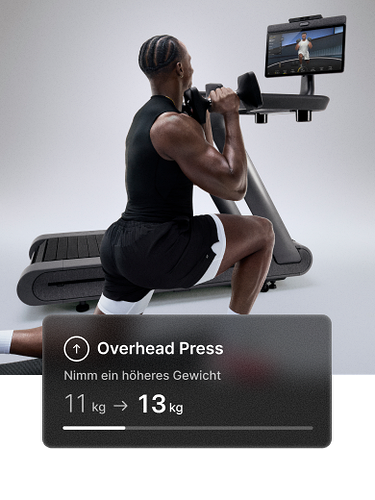 Ein Mann macht einen Ausfallschritt mit Hanteln vor einem Peloton Row+. Das Overlay empfiehlt: „Versuche ein schwereres Gewicht — 7 kg → 9kg.“