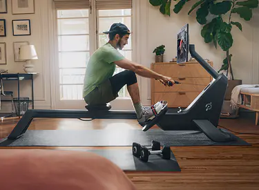 Man rowing on his Peloton Row at home