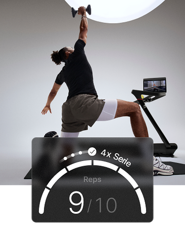 Ein Mann kniet auf einer Matte und streckt einen Arm über den Kopf, während er eine Hantel hält, neben einem Peloton Tread+. Das Overlay zeigt „Wiederholungen 5/6“.