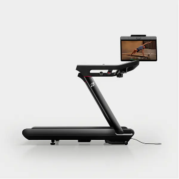 Side profile of a Peloton Tread treadmill featuring a sleek black frame and front-mounted touchscreen.