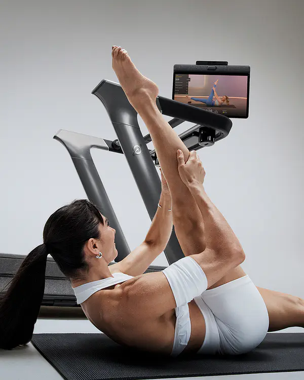 woman doing yoga beside the peloton tread plus