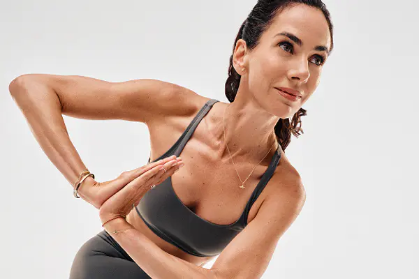 Yoga instructor holding hands in prayer position while performing a side twist pose.
