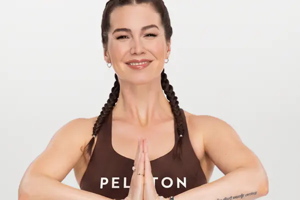 Yoga instructor holding hands in prayer position while performing a side twist pose.