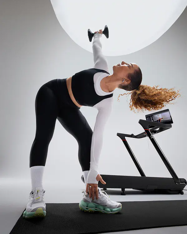 woman lifting weight next to peloton tread