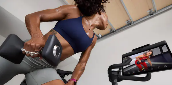 woman lifting weight while taking a peloton class