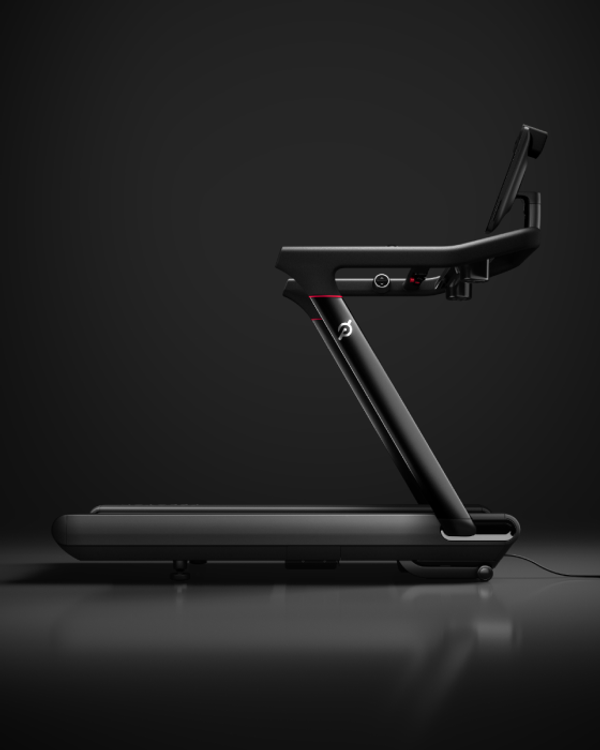 Side profile of a Peloton Tread treadmill on a dark background.