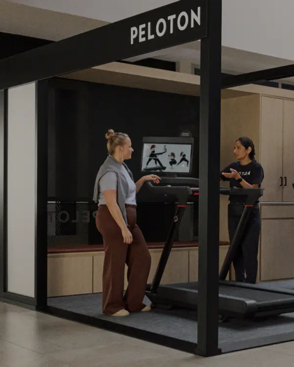 ustomers trying out Peloton treadmills in a modern indoor retail showroom.