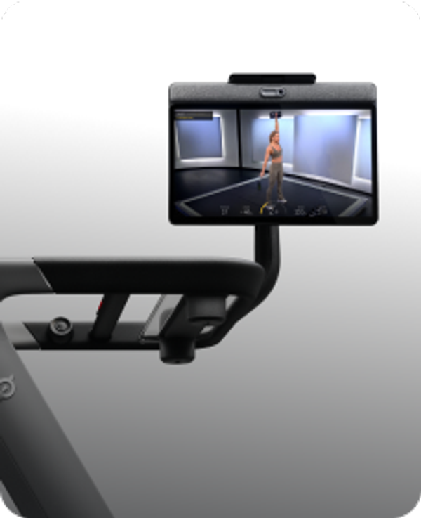 Peloton Tread screen displaying an instructor leading an overhead dumbbell press workout in a studio.