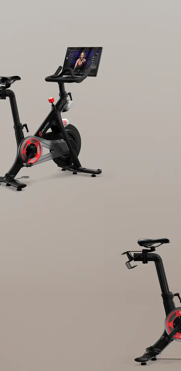 Two Peloton bikes, one showing the front handlebars and screen, and the other showing the seat and frame, on a neutral background.