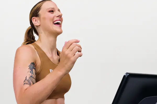 Walking instructor smiling while walking on a Peloton Tread treadmill.