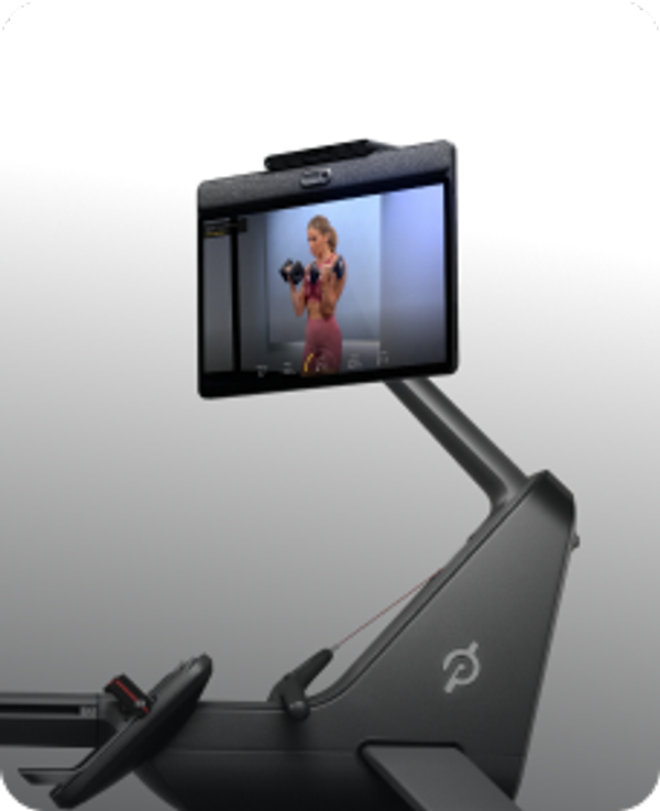 Peloton Row screen featuring an instructor demonstrating dumbbell bicep curls during a strength class.