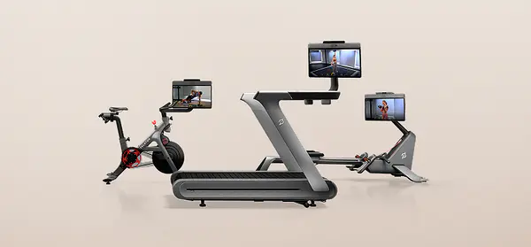 Peloton Bike+, Tread+, and Row+ machines arranged against a neutral background, each displaying a workout class on its screen.