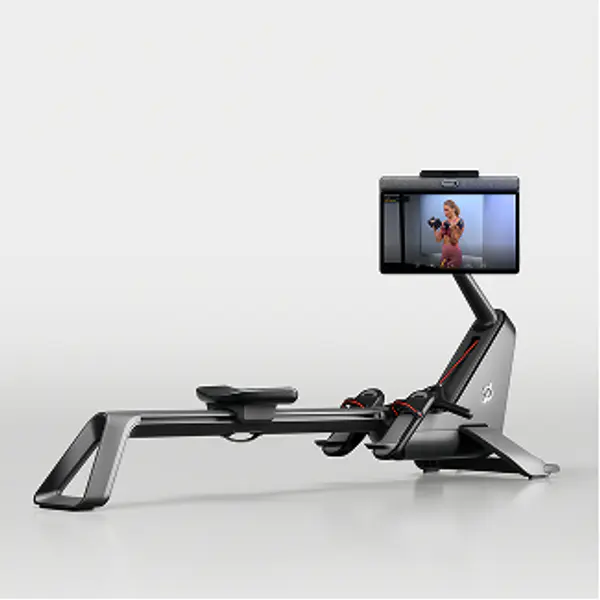 Peloton Row machine viewed from the side, showing the sliding seat, rail, and attached workout screen.