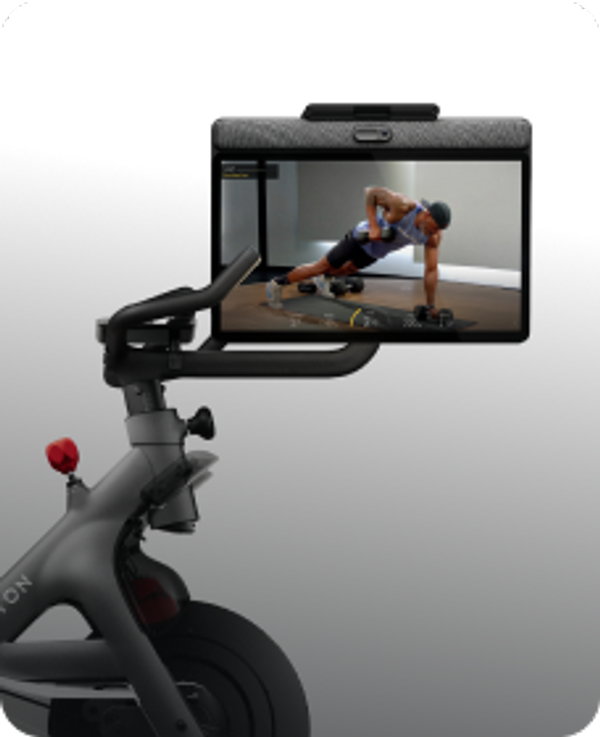 Peloton Bike screen showing an instructor performing a single-arm dumbbell row in a plank position.
