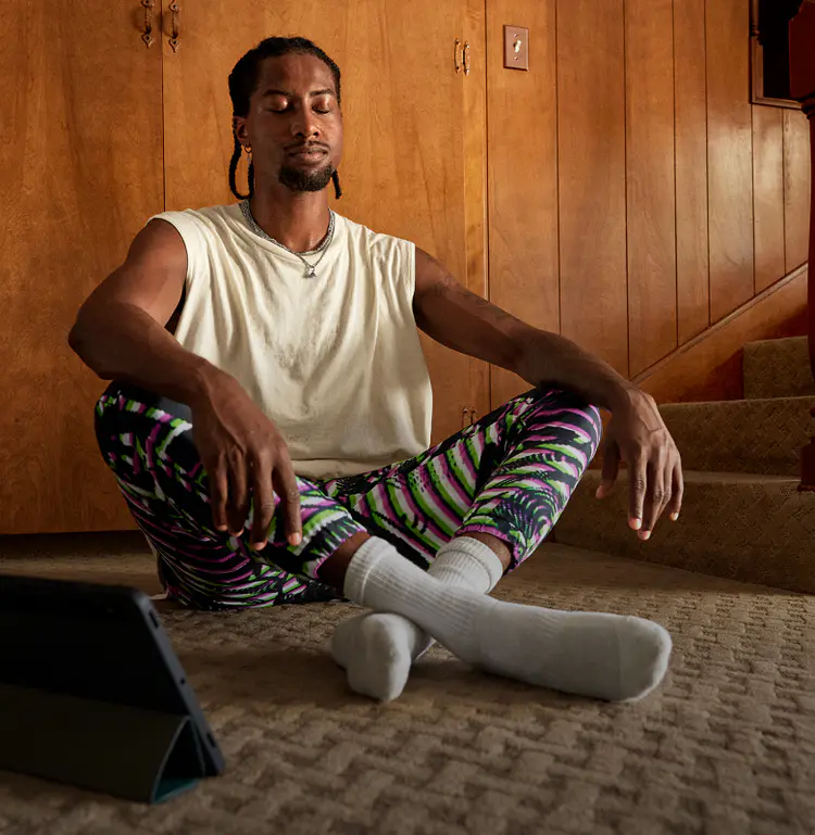 Man meditating on the floor with the Peloton App