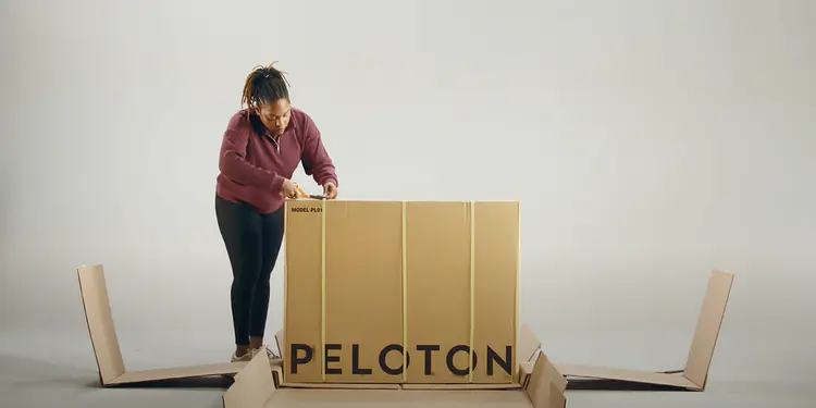 women unboxing a Peloton bike