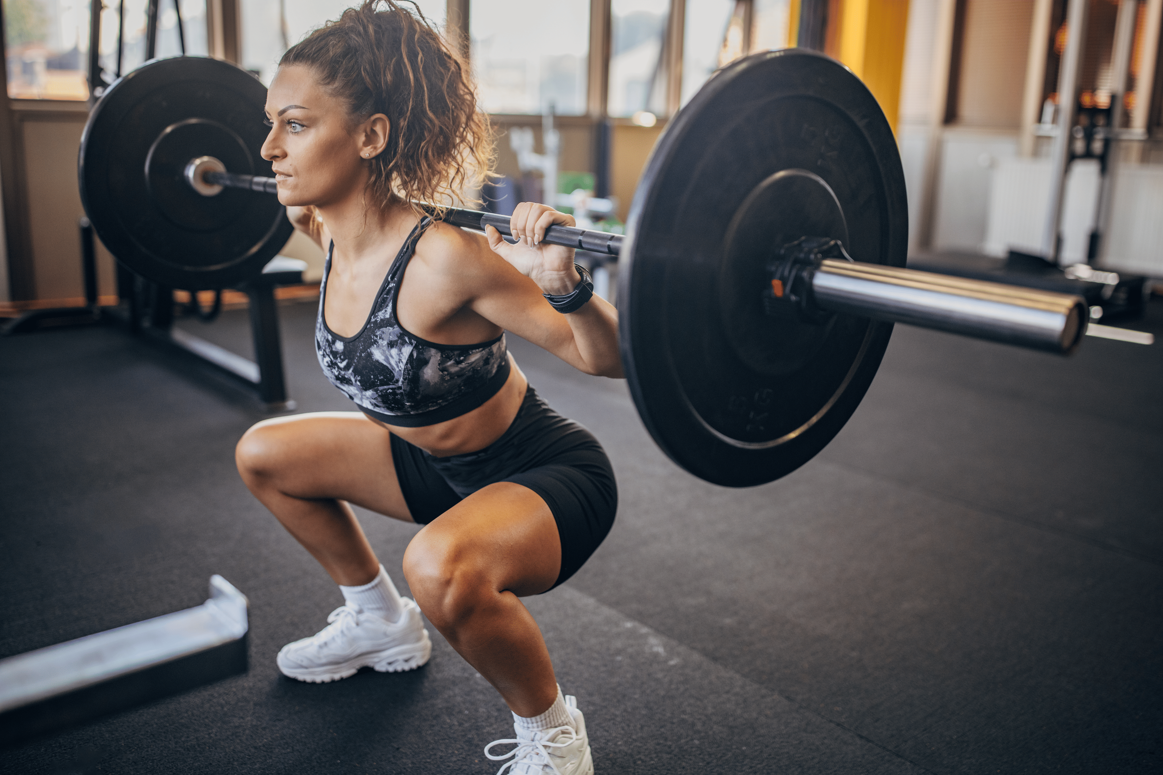 Woman does a barbell squat in gym
