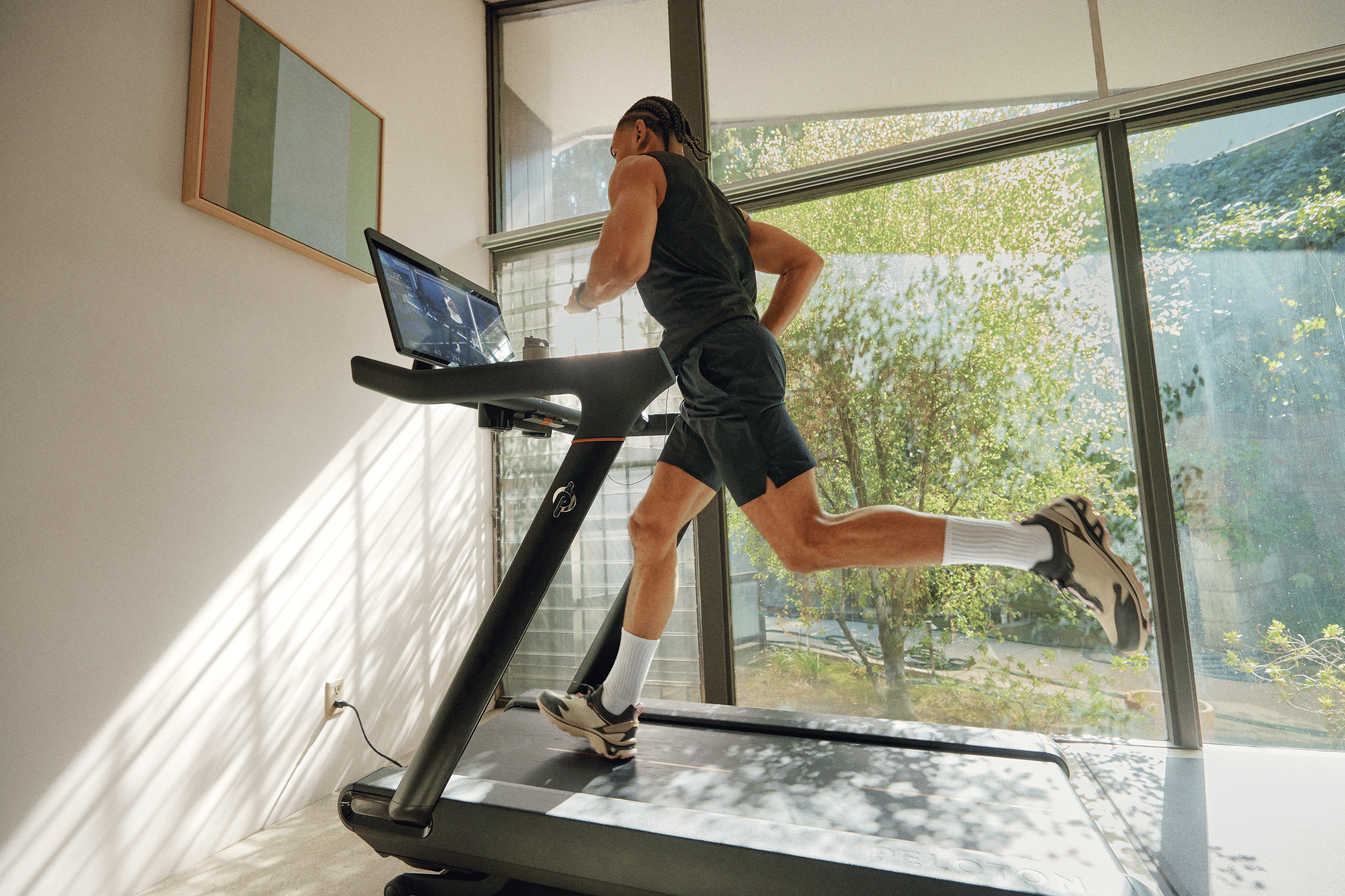 Man running strides on a Peloton treadmill in his home.