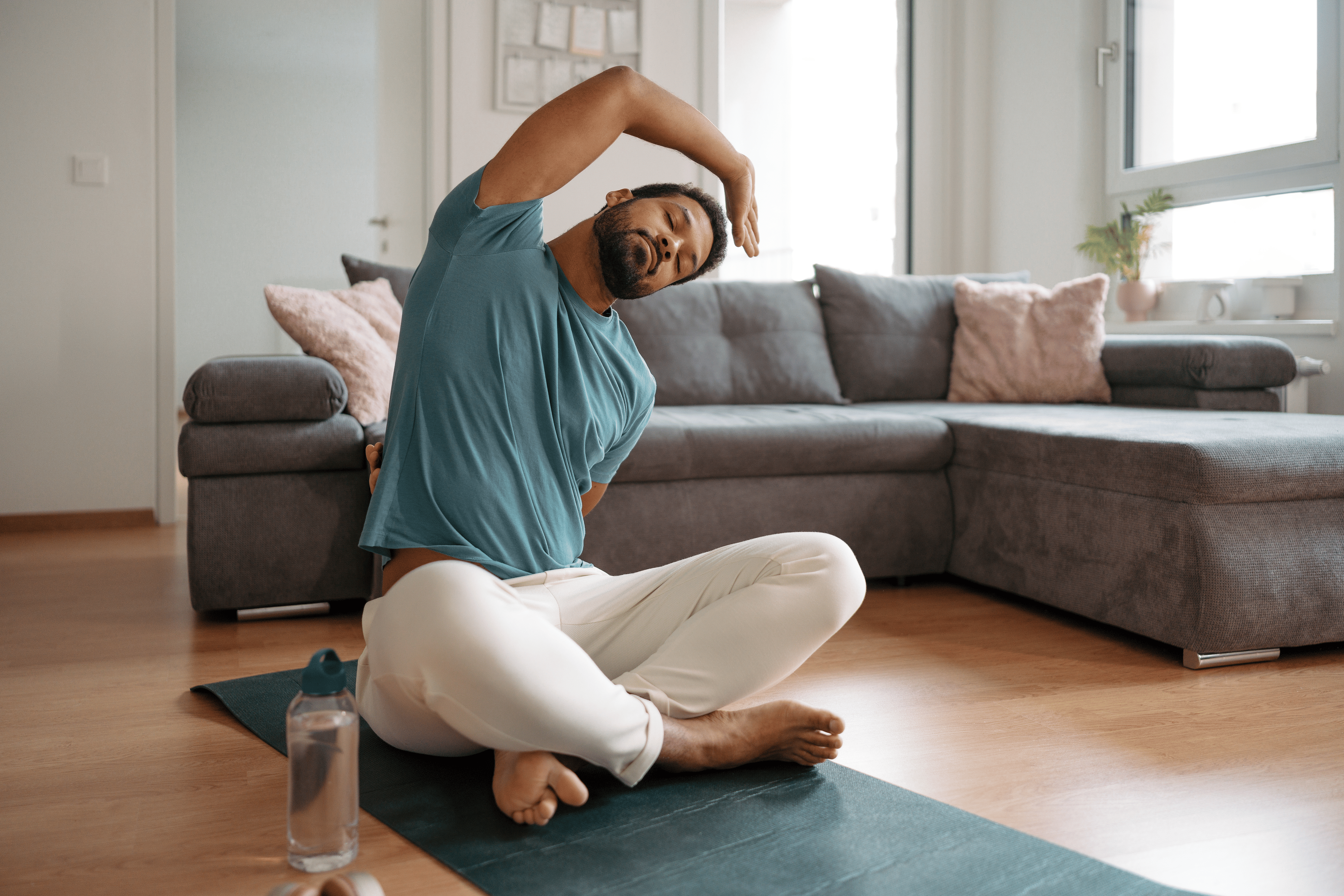 A man trying to stretch his quadratus lumborum at home using QL stretches and exercises like a seated side bend.