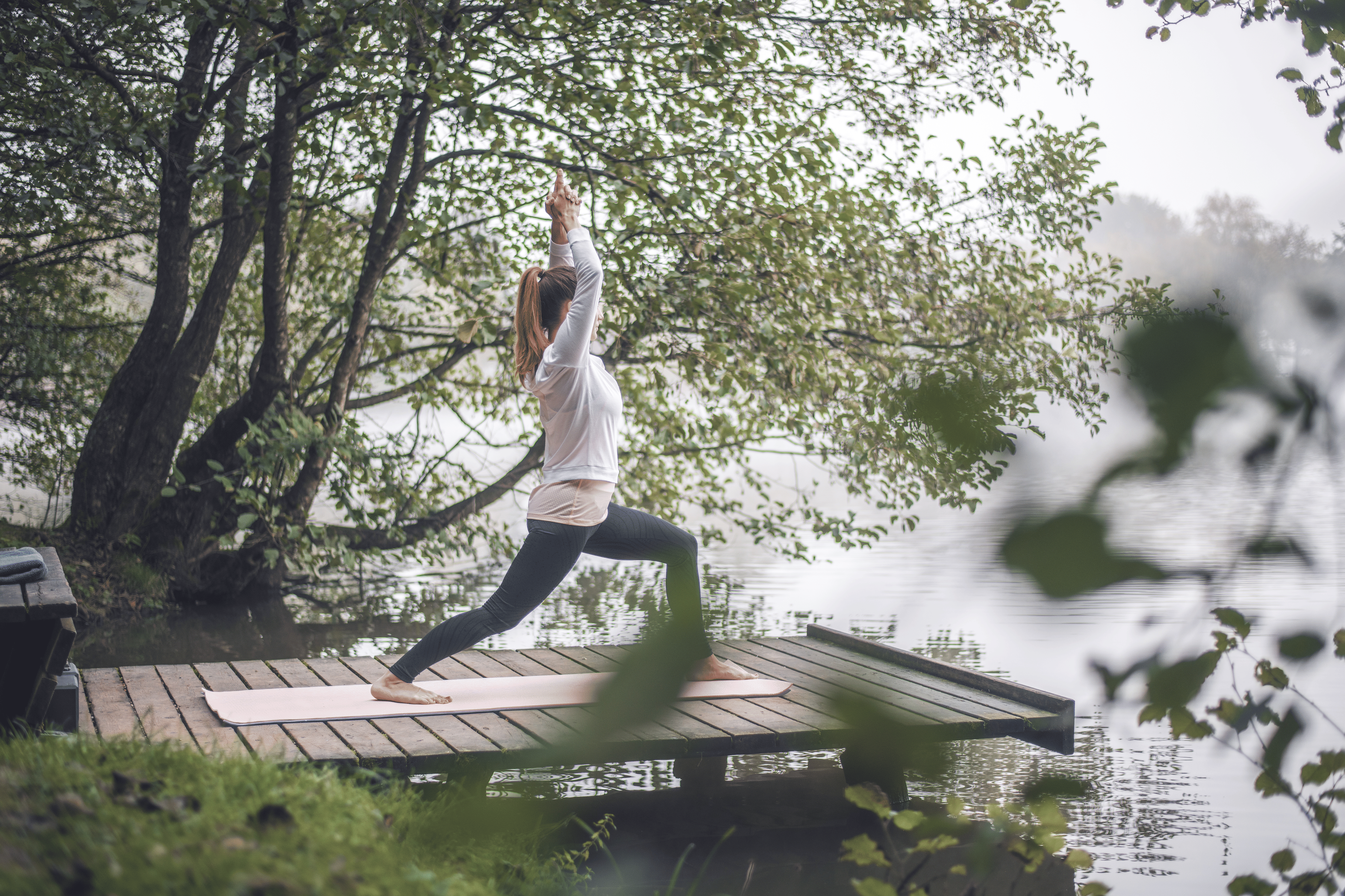 Woman doing Warrior One Yoga Pose in Woods