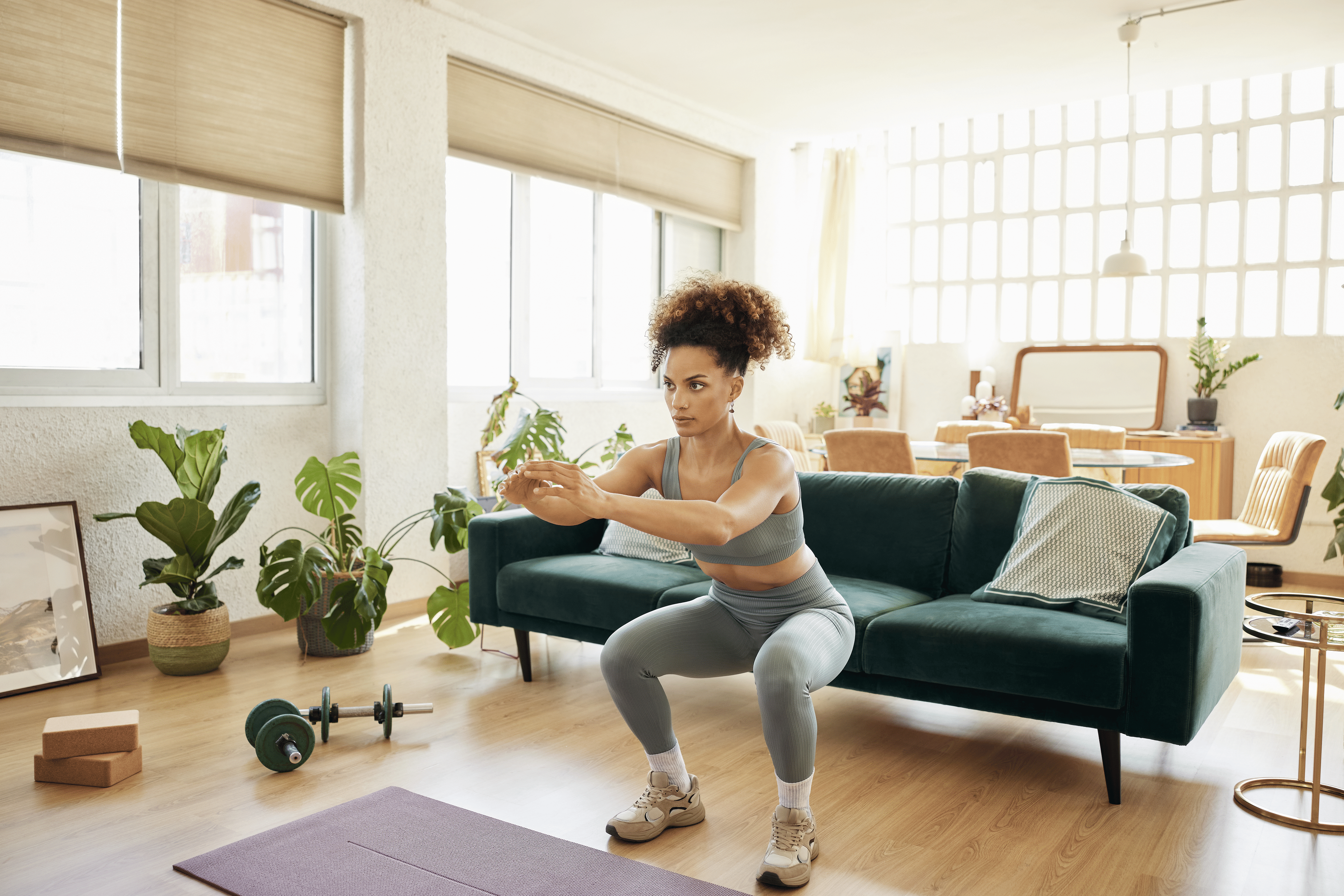 Young woman does squats in living room 