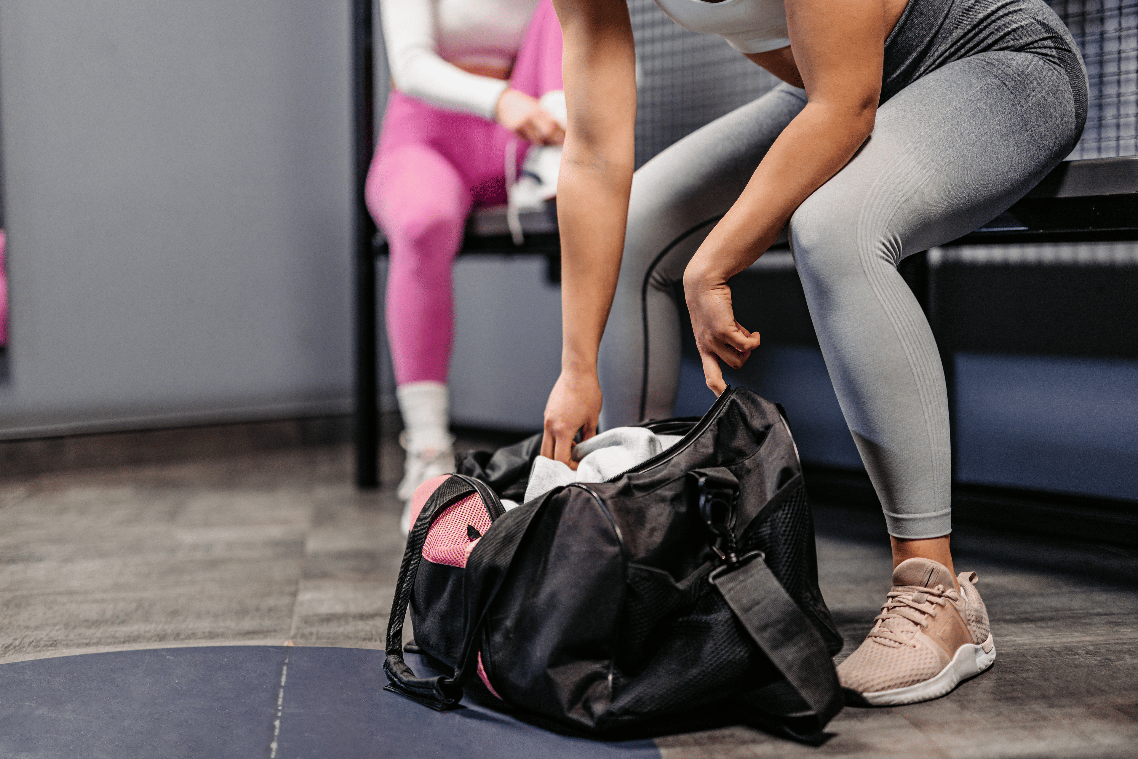 Woman opening up gym bag in a locker room 