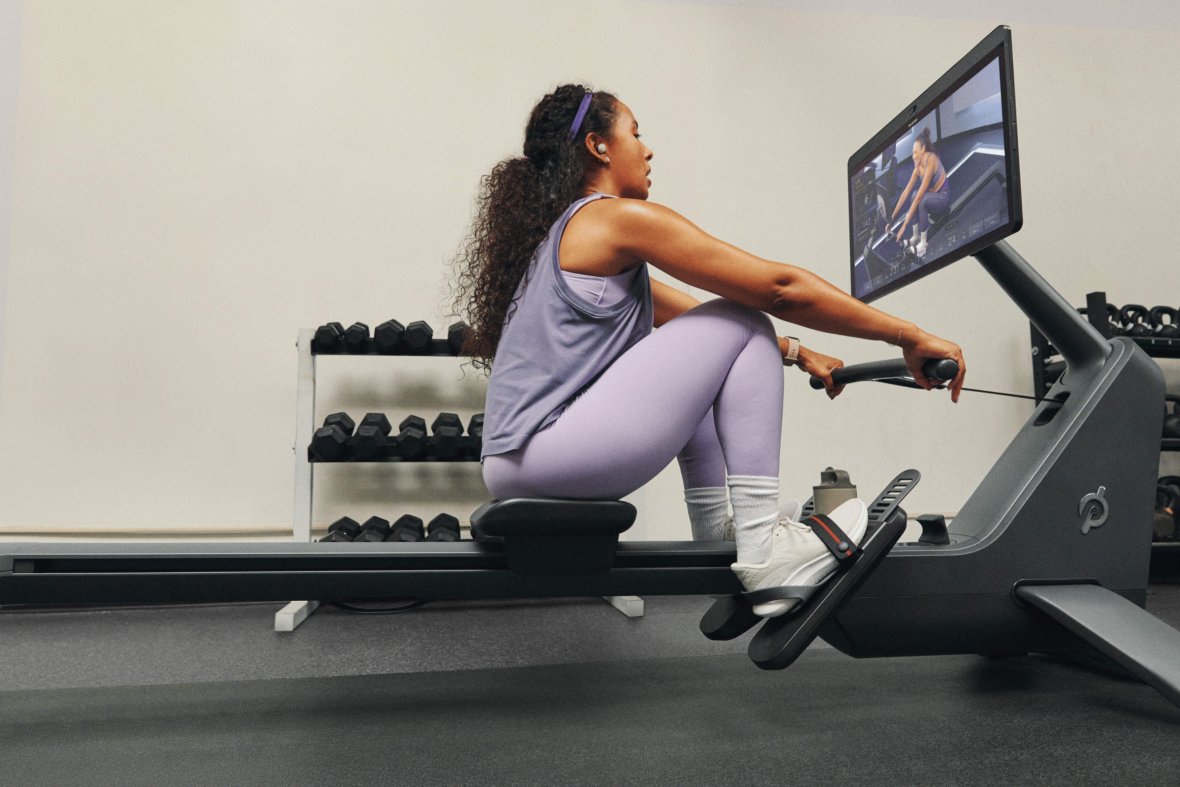 Woman doing a Peloton rowing machine workout class on a Peloton Row