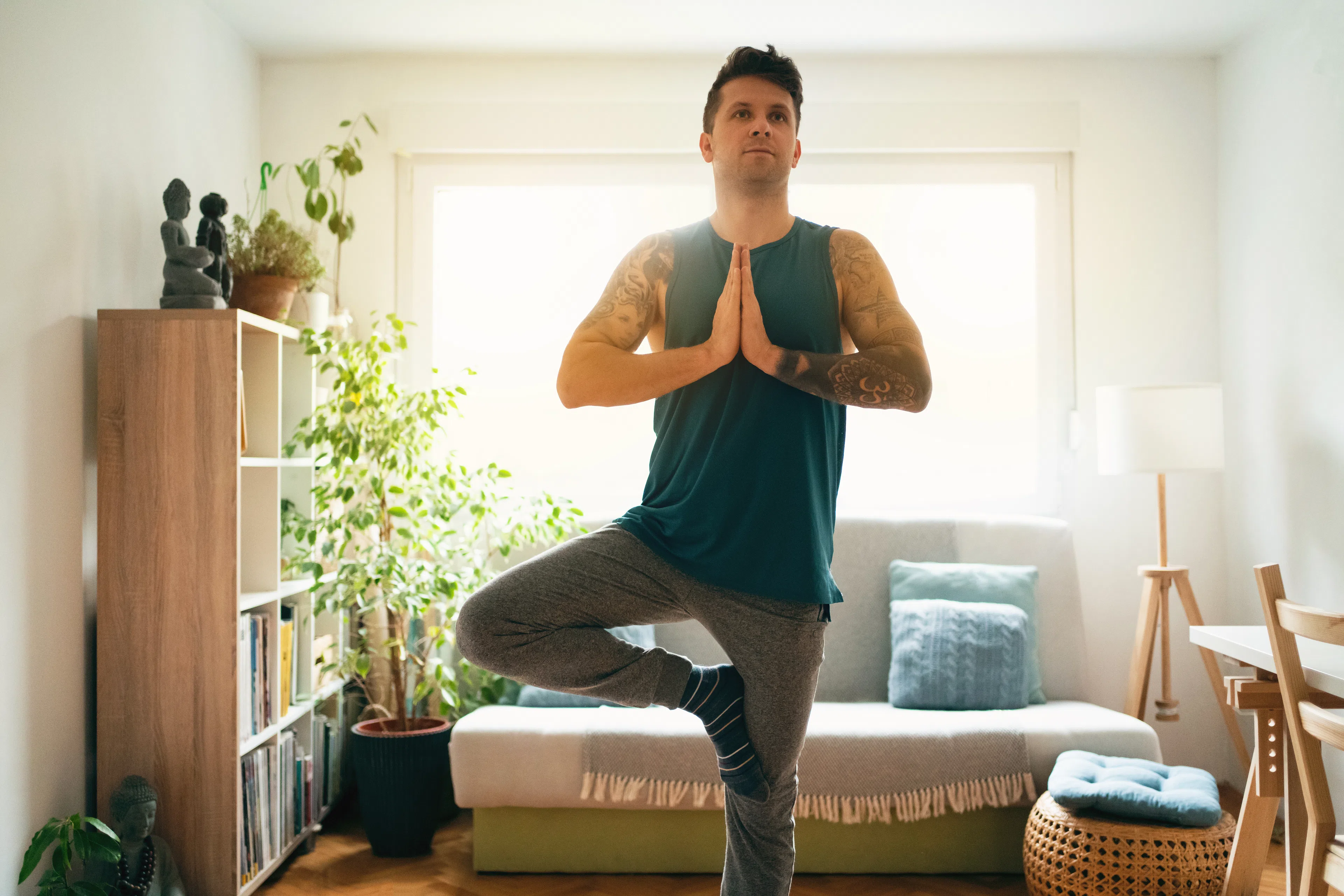 Man doing Tree Pose (yoga posture) inside 