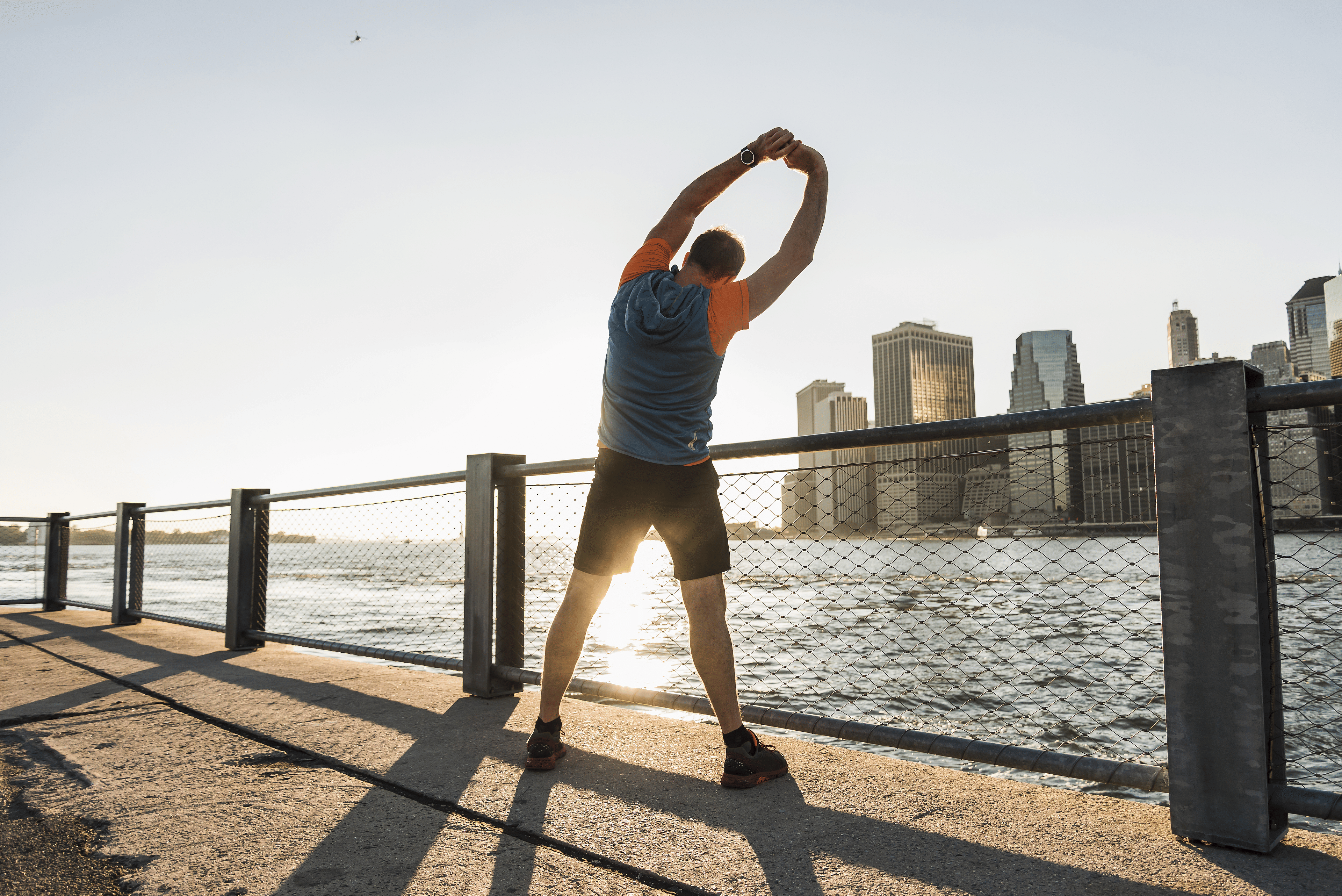 Man does an overhead reach lat stretch outdoors