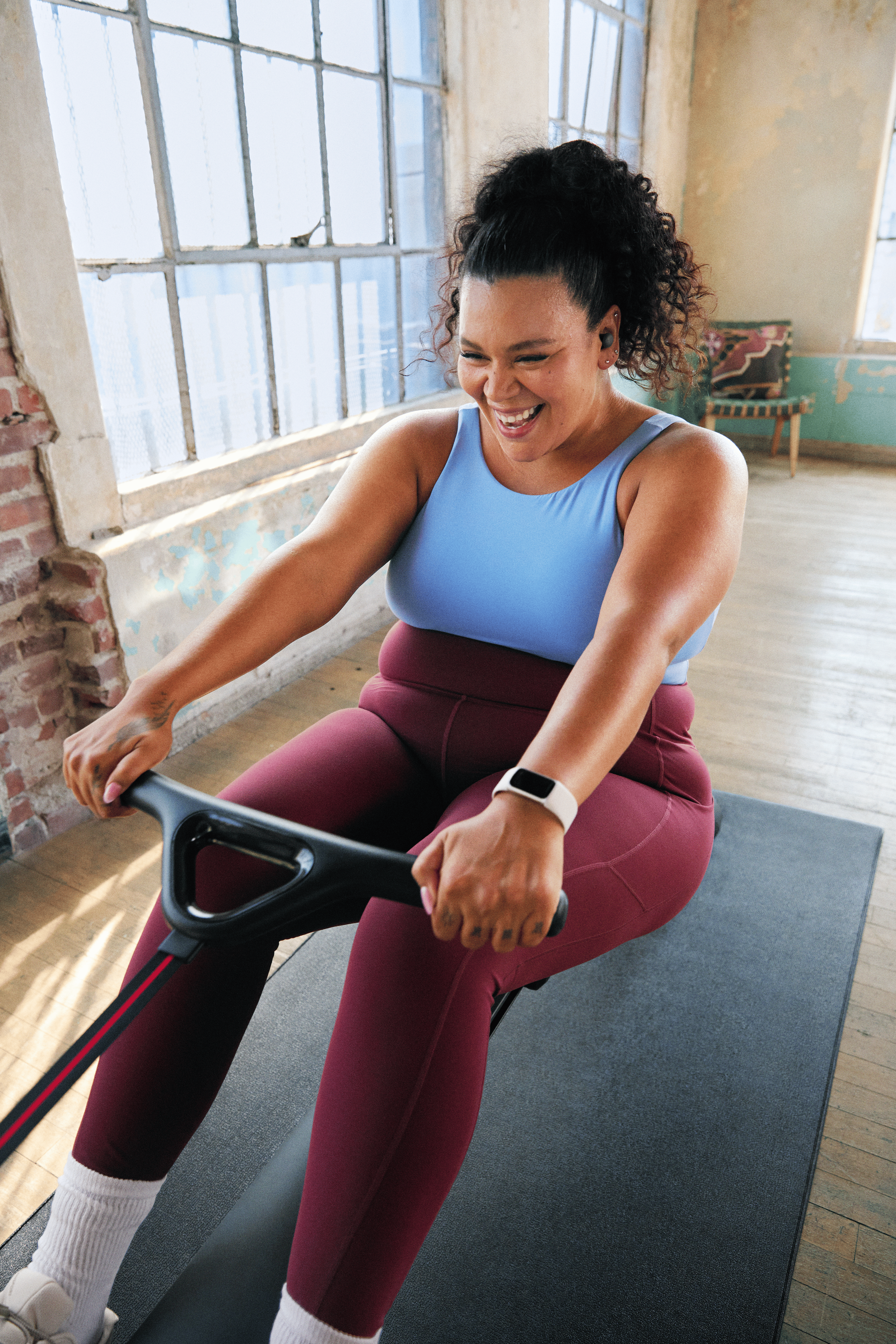 Woman smiling while doing a rowing machine workout on the Peloton Row