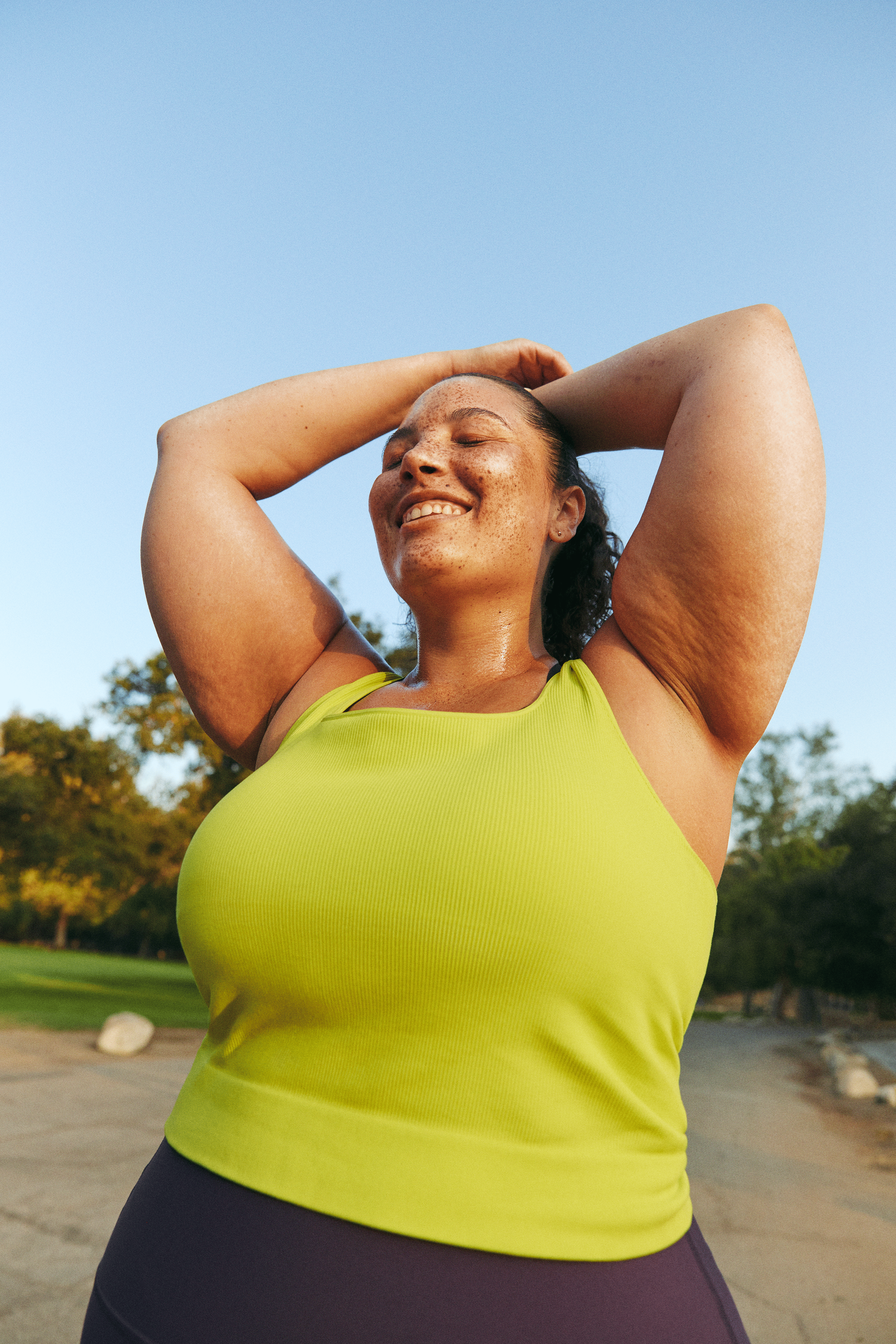 Woman resting with her arms over her head during a run while feeling the mental health benefits of running.